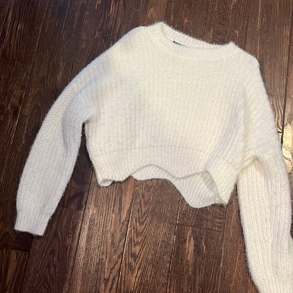 Basic white sweater with squiggle cut off bottom.